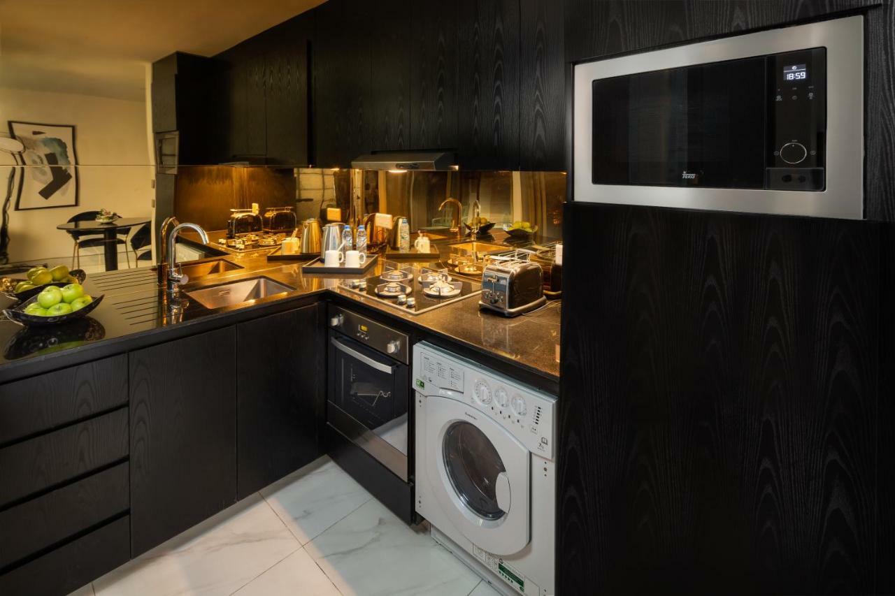 الشقق الفندقية دبيفي  ميلينيوم أتريا بيزنس باي المظهر الخارجي الصورة The photo shows a modern kitchen with a sleek design. The cabinets and surfaces are predominantly black, creating a contemporary look. There is a stainless steel microwave mounted above the countertop, and on the counter, various kitchen appliances l